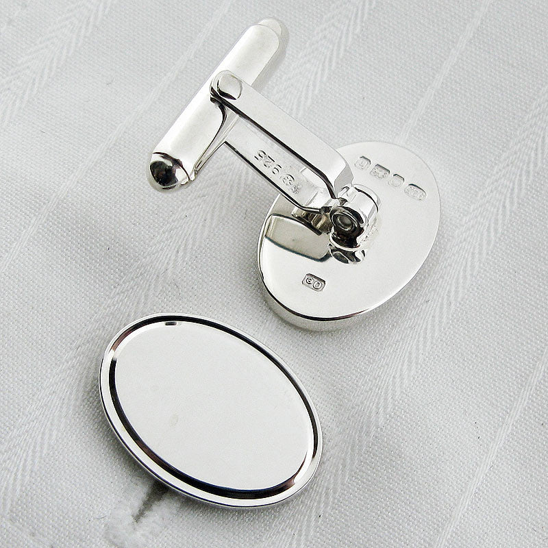 Oval silver cufflinks with engraved border showing backs